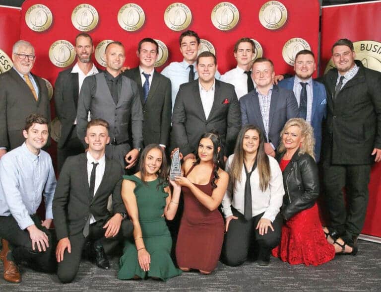 A group of people posing for a photo in front of a red wall.
