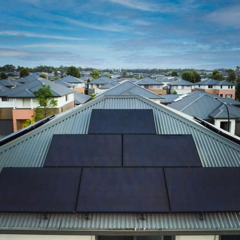 Residential solar: a view of a home with solar panels. Other homes without solar panels are in the background.