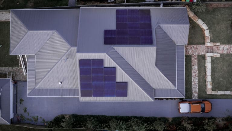 An aerial view of a house with solar panels on the roof.