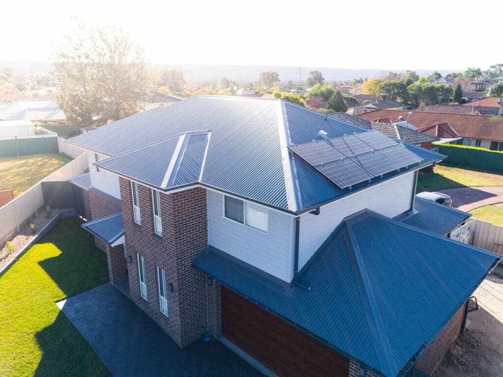 An aerial view of a house with solar panels on the roof.