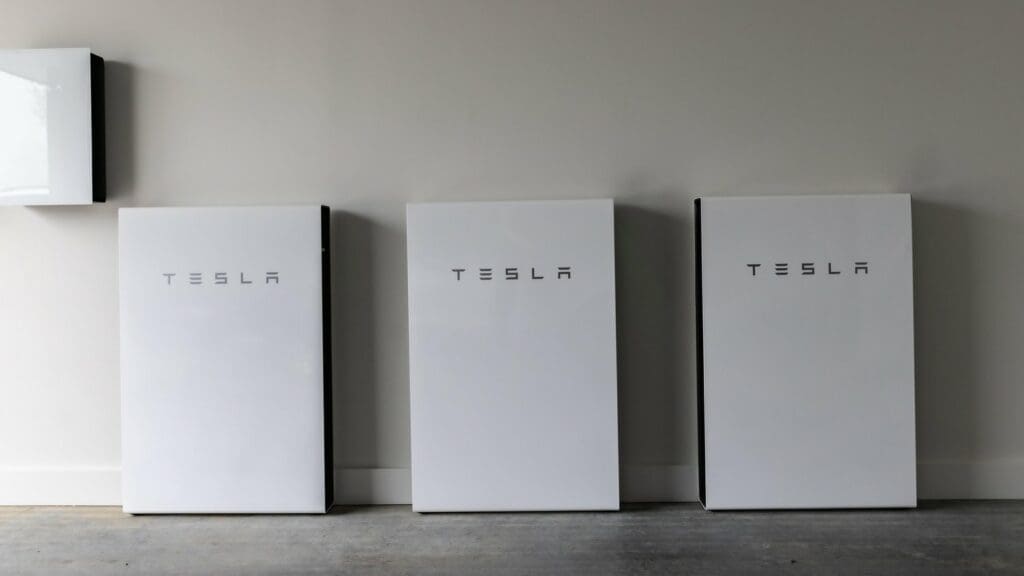 Three tesla powerwalls are lined up against a wall.