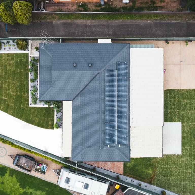 An aerial view of a house with solar panels on the roof.