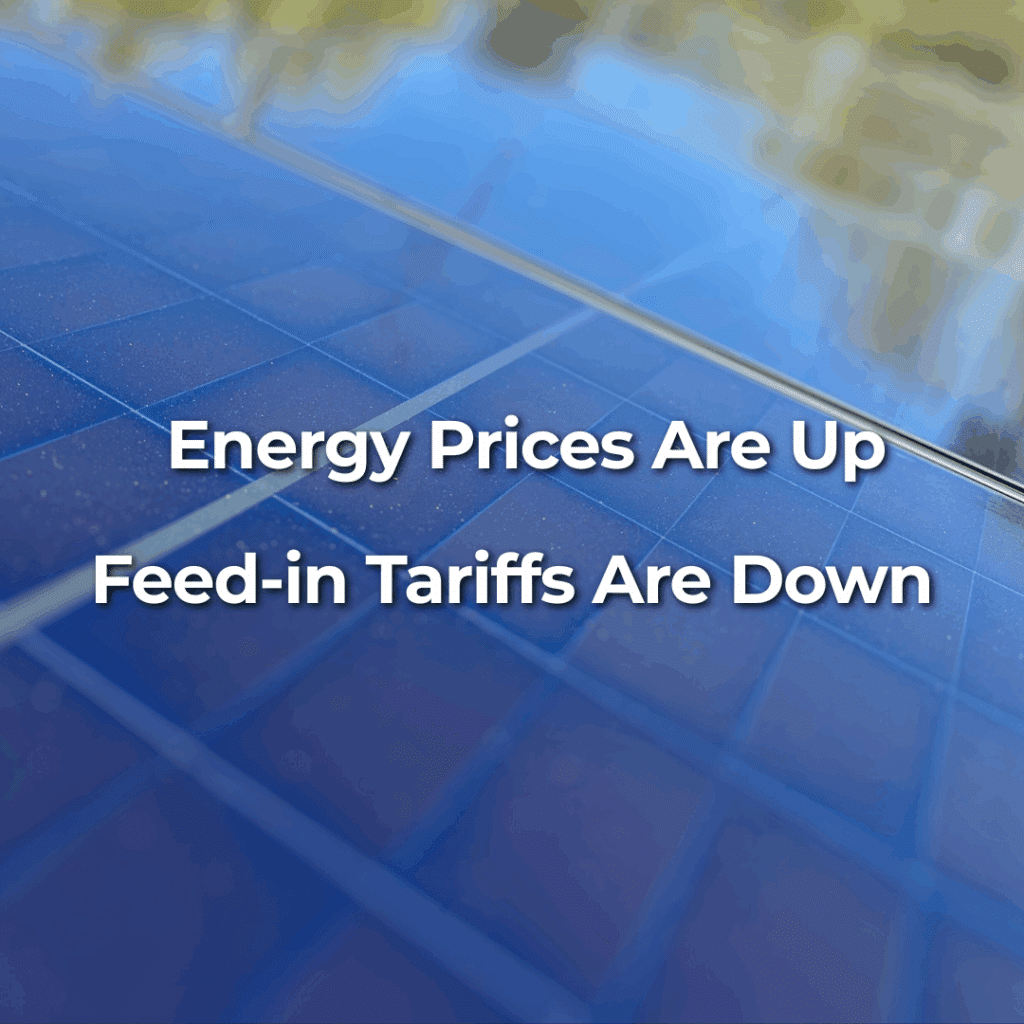 Close-up of solar panels with the text "Energy Prices Are Up, Feed-in Tariffs Are Down" displayed over the image.