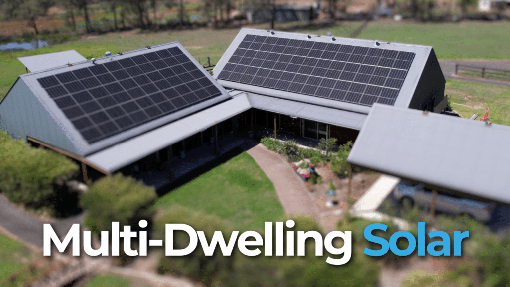 Aerial view of a multi-dwelling complex with solar panels on the roofs, surrounded by greenery, with the text "Multi-Dwelling Solar.